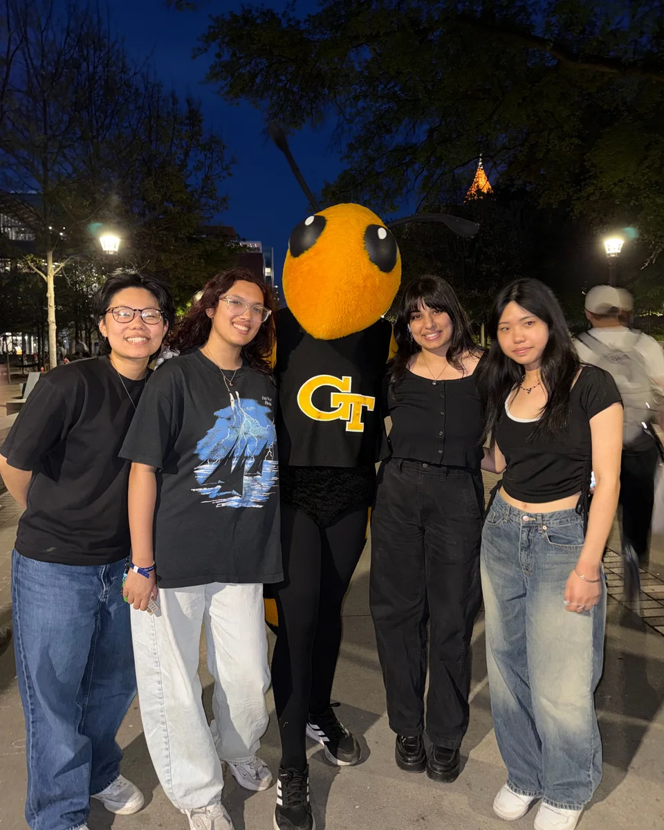 Anya and three friends at night on the Georgia Tech campus, posing with Buzz, the yellow jacket mascot.