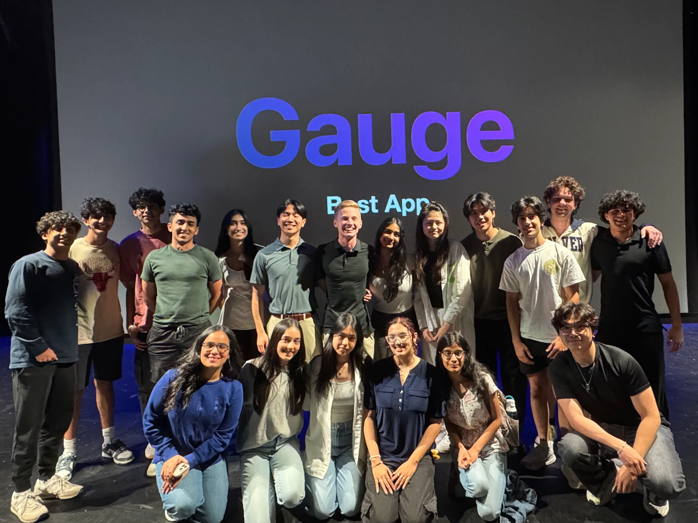 The Gauge team on stage at Demo Day, in front of a screen reading “Gauge, Best App”.
